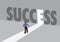 Businessman walking towards a light path with the text success. Business concept of business success, innovation or overcoming