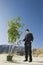 Businessman Watering Plant In Desert