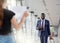 Businessman waving to a partner who waiting for him with name sign on paper