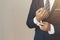 Businessman wearing business suit fasten cufflink or button on sleeve of classic jacket and factory background