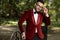 Businessman wearing red tuxedo standing and fixing eyeglasses