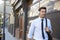 Businessman Wearing Wireless Headphones Walking To Work