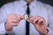 A businessman in a white shirt and black tie holds a physical version of bitcoin in his hands