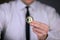 A businessman in a white shirt and black tie holds a physical version of bitcoin in his hands