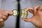 A businessman in a white shirt and black tie holds a physical version of bitcoin in his hands