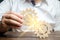 Businessman in white shirt connects two wooden gears. Symbolism of establishing business processes and communication. Increase