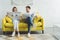 Businessman with wife reading newspapers about travel and business while sitting on sofa in modern room