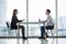 Businessman and woman having a discussion in the office face to face at table against windows