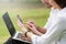 Businessman and woman use laptop and smartphone in park, sit on