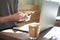 Businessman working alone on laptop and using mobile smartphone in sunny cafe, having coffee. Focus on manâ€™s hands