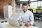 Businessman working on computer. Young smiling man using laptop in the office. Internet marketing, finance, business concept