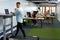 Businessman working on laptop while exercising on treadmill in a modern office