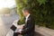 Businessman working with laptop outside near plant in .