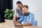 Businessman working on laptop with smiling colleague in office