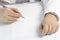 Businessman writes on a sheet of white paper. Dressed in a shirt and tie. Close-up