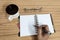 Businessman writing in his diary. Open notebook with blank pages next to cup of coffee and eyeglasses on wooden table. Business