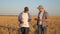 Businessmen farmers discuss the wheat crop on the field and view the schedule on the tablet. Ripening grain and