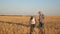 Businessmen farmers discuss the wheat crop on the field and view the schedule on the tablet. Ripening grain and