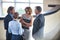 Businessmen greeting while standing with colleagues at reception lobby in office