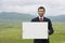 Businessmen Holding Blank Sign In Mountain Field