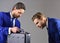 Businessmen look into opened black briefcase on dark background.