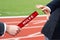 Businessmen pass help baton in German Hilfe relay race in stadium