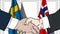 Businessmen or politicians shake hands against flags of Sweden and Norway. Official meeting or cooperation related