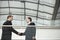 Businessmen Shaking Hands Against Glass Railing