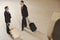 Businessmen With Suitcases By Luggage Carousel In Airport