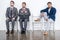 Businessmen in suits sit on chairs at white waiting room