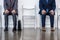 Businessmen in suits sitting on chairs at white waiting room