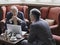 Businessmen Talking Over Laptop In Lobby