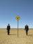 Businessmen Walking Past Road Sign In Desert