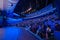 Businesspeople attending global seminar in illuminated blue auditorium