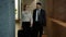 Businesspeople man and woman leaving hotel with luggage walking in lobby talking