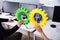 Businesspeople`s Hand Joining Green And Yellow Gears