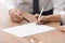 Businesspeople signing contract at wooden table, closeup