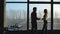 Businesspeople silhouettes standing against panoramic office window