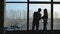 Businesspeople silhouettes standing against panoramic office window