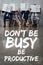 Businesspeople sitting on chairs and holding newspapers in front of faces in waiting hall with dont be busy be productive letterin