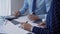 Businesspeople working at a grey glass table. Two accountants or auditors are using a calculator for counting taxes or