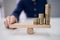 Businessperson Balancing Coins On Wooden Seesaw