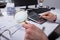 Businessperson Examining Invoice Through Magnifying Glass