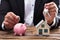 Businessperson holding coin and key over piggybank and house