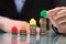 Businessperson Placing Green House Model On Top Of Stacked Coins