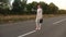 Businesswoman with black briefcase walks in light suit and white high-heeled shoes goes outside city along asphalt with