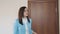 Businesswoman brunette in a blue jacket opens the door and comes into her office.