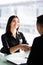 Businesswoman and businessman shaking hands over the table with laptop and papers at the office, pleasant business meeting, starti