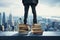 Businesswoman and businessmans feet atop stacked books against a city backdrop