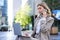 Businesswoman checking diagram and work on laptop, calling someone on mobile phone, sitting outdoors in city centre